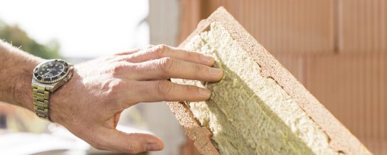 Hand touching mineral wool of internal insulation filled clay block