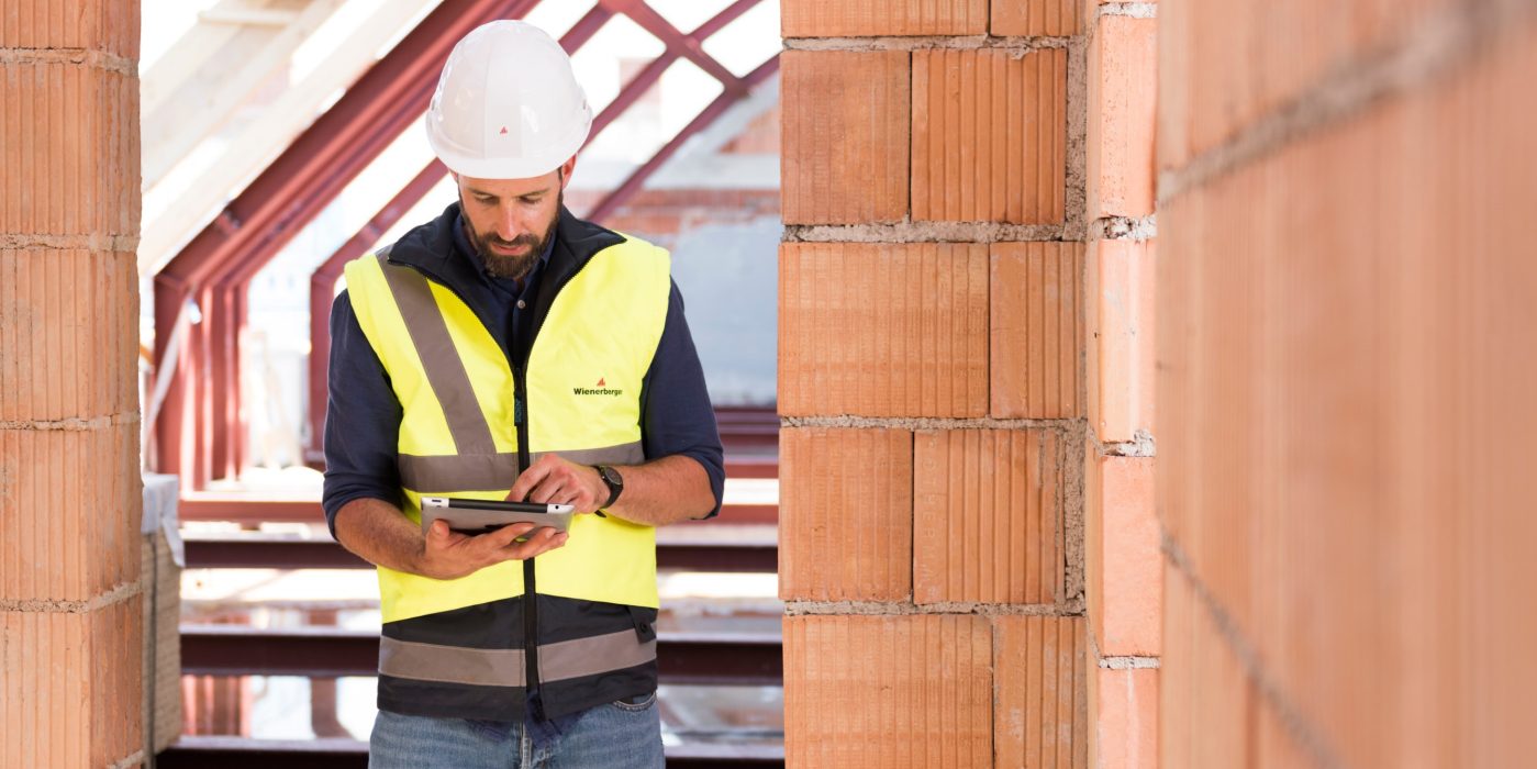 Product manager standing in attic under renovation checking tablet