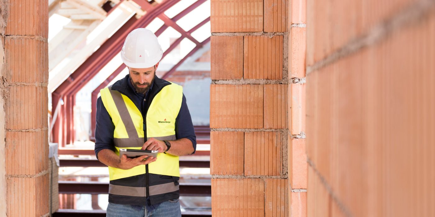 Product manager standing in attic under renovation checking tablet