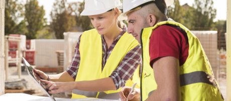 Woman pointing at tablet with male coworker taking notes at construction site, Fast Forward Commercial Excellence