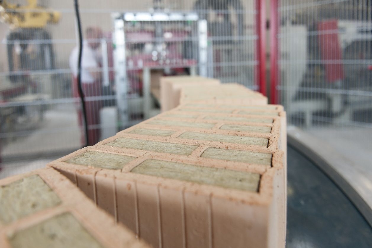 Insulation filled clay blocks on conveyor belt leaving filling station at production plant Haiding