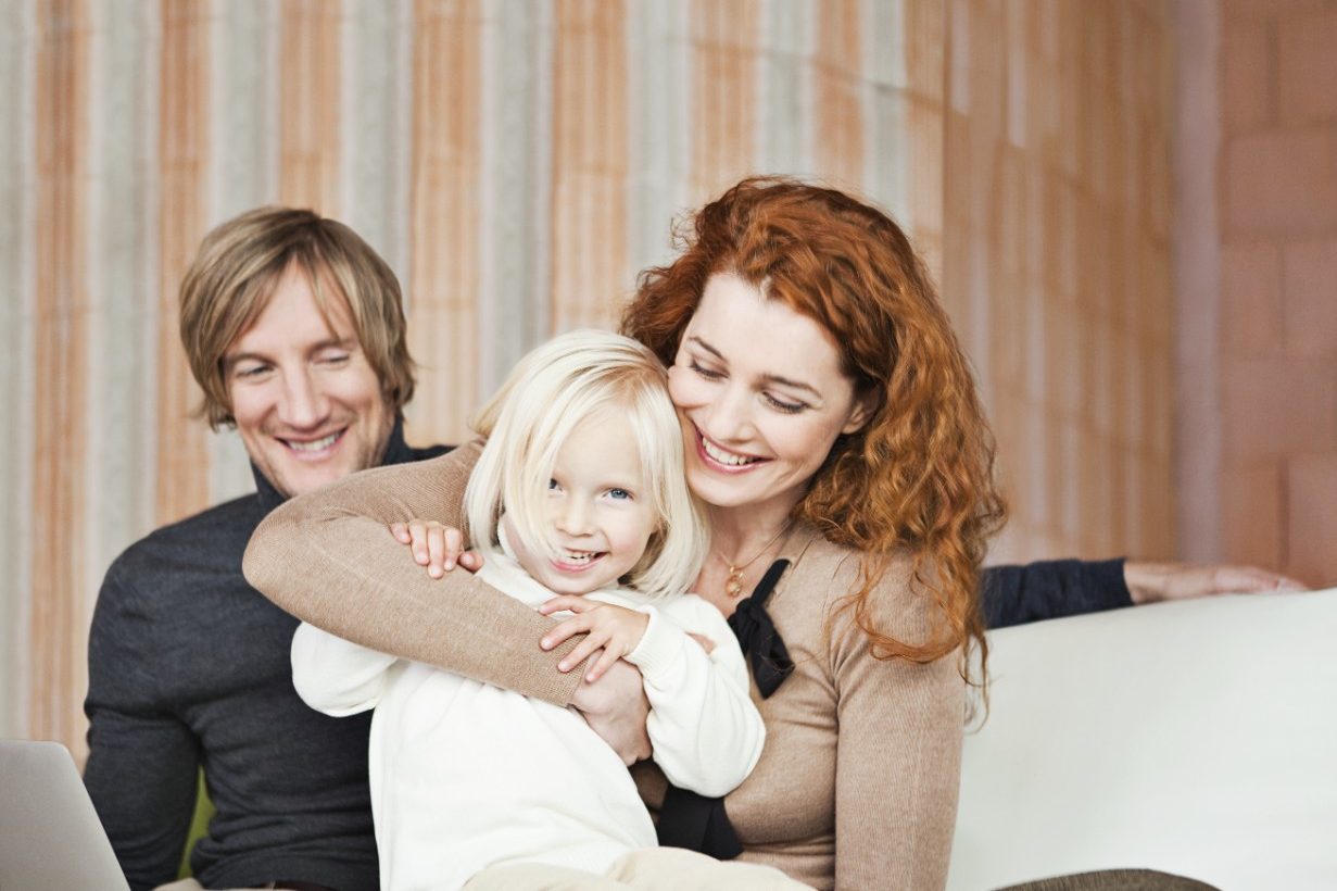 Couple with young girl inside unfinished building surrounded by bare brickwork