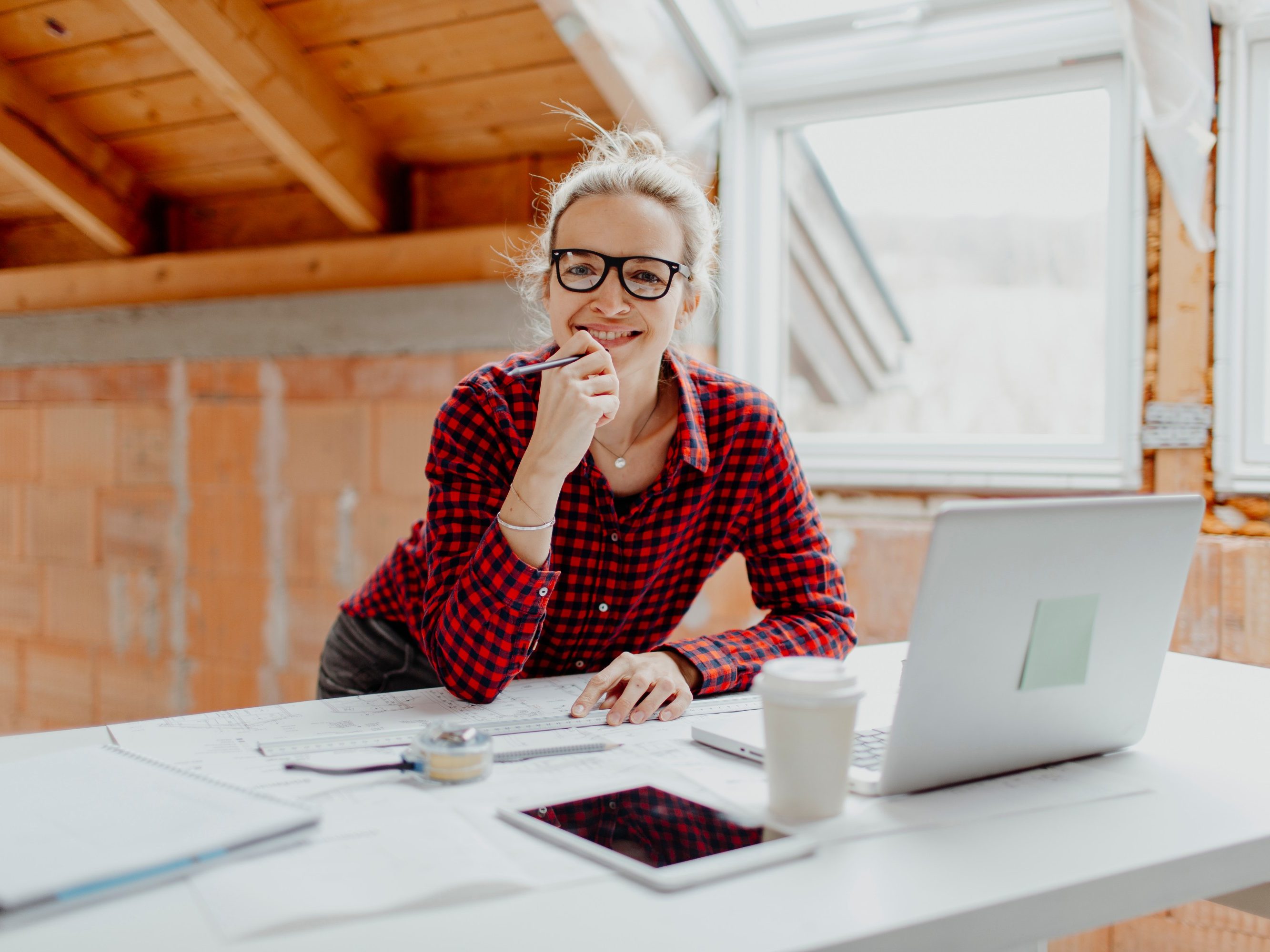 beautiful young, pretty, blonde woman is planning on the notebook and tablet the expansion of her loft